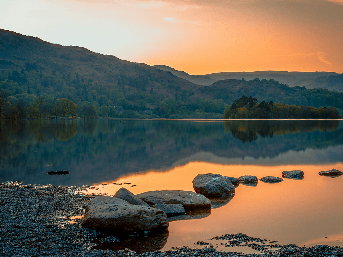 Stepping stones leading out across a calm lake at sunset